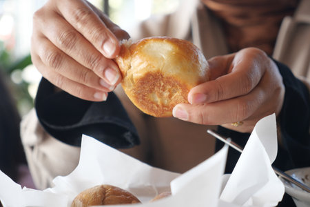Hands holding freshly baked pastry in a cozy cafe settingの写真素材