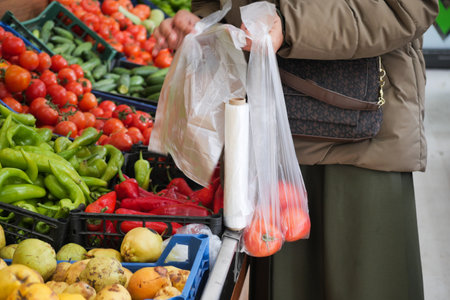 Shopper selecting fresh vegetables at a bustling market stallの写真素材