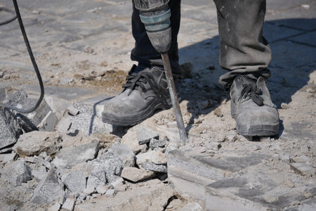 Worker using pneumatic tool to break concrete at construction siteの写真素材