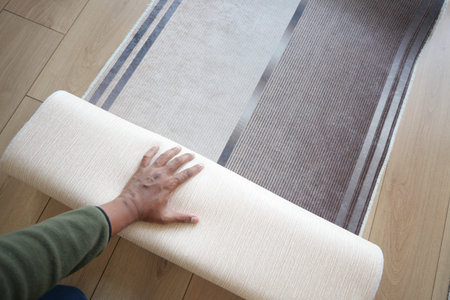 Homeowner unrolling a new rug on hardwood floor in living room