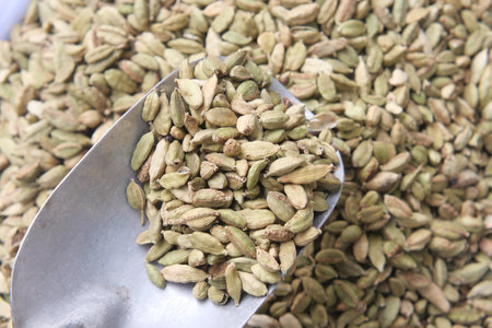 Cardamom pods displayed in a metal scoop at a spice marketの写真素材