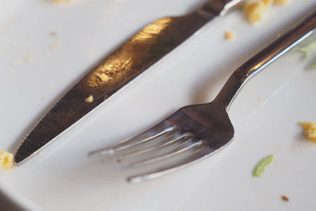 Dining utensils on a plate after a meal in a restaurant settingの写真素材