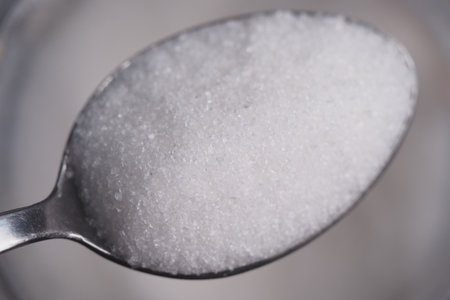 Close-up of white sugar on spoon in kitchen settingの写真素材