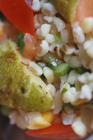 Colorful grain salad with fresh vegetables and herbs in bowlの写真素材