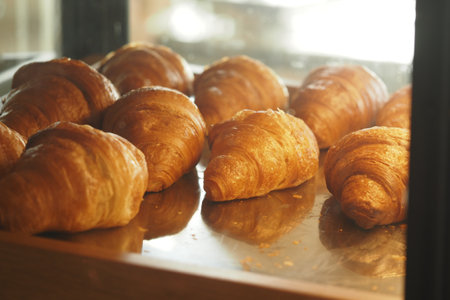 Freshly baked croissants displayed in a cafe bakery showcaseの写真素材