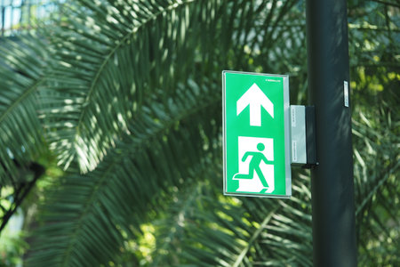 Emergency exit sign indicating direction in a tropical settingの写真素材