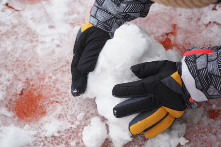Child building a snowball during winter playtime outsideの写真素材