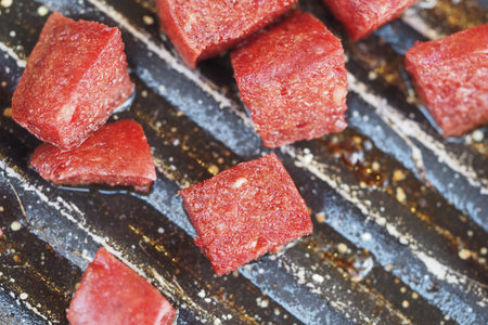 Frozen beef cubes ready for cooking on a grill surfaceの写真素材