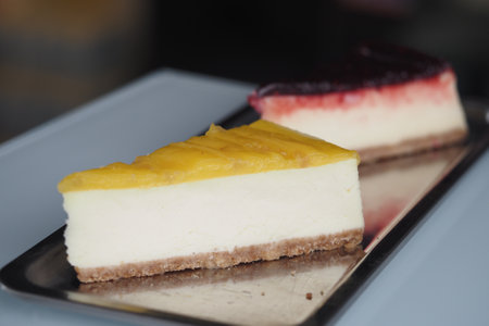 Delicious cheesecake slices with fruity toppings on a trayの写真素材