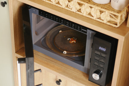 Microwave in kitchen showing food splatters inside during meal prepの写真素材