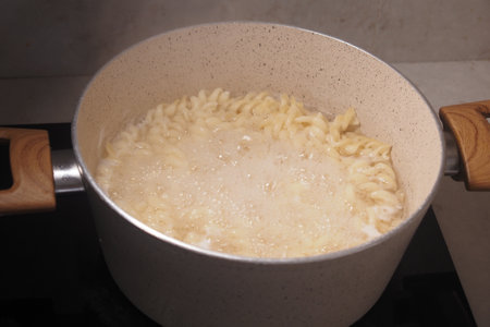 Cooking pasta in a pot on a stovetop in a modern kitchen settingの写真素材