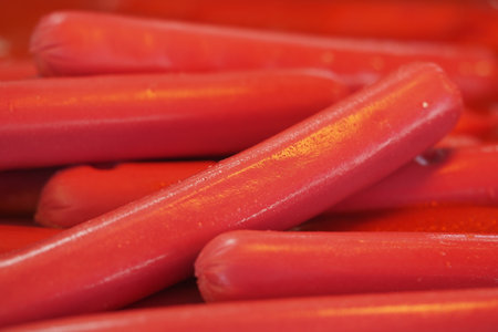 Bright red hot dogs stacked in a casual food settingの写真素材