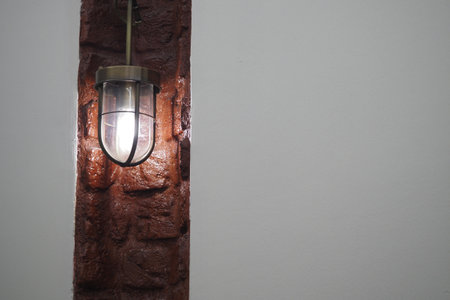Warm light fixture illuminating a textured wall in interior spaceの写真素材