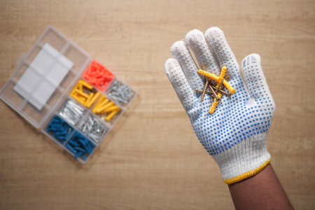 Hand holding construction fasteners with organized toolbox nearbyの写真素材