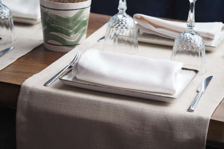 Elegant dining setup with white linens and glassware before mealの写真素材