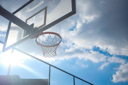 Basketball hoop under a bright sky at outdoor court during the dayの写真素材
