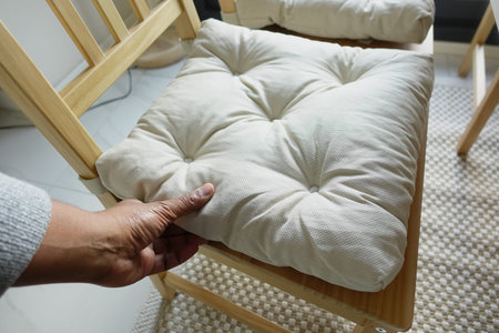 Comfortable chair cushion being arranged in a cozy living spaceの写真素材