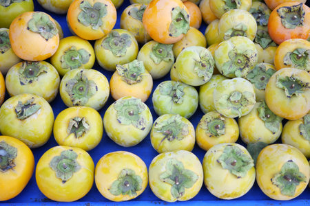 Persimmons arranged neatly on display at a local market in autumnの写真素材