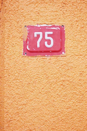 Numeric house number 75 displayed on vibrant orange wallの写真素材