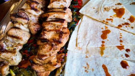 Grilled chicken skewers served with vegetables and tortillas on plate