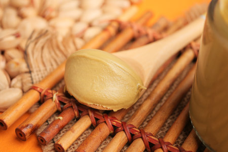 Pistachio butter spread on a wooden spoon with nuts backgroundの写真素材