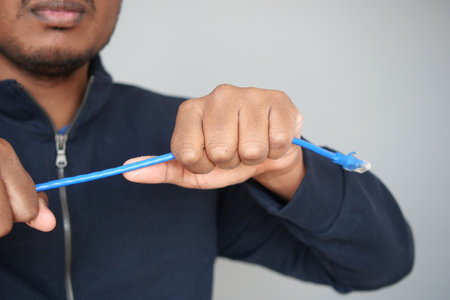 Man cutting an Ethernet cable with his hands indoorsの写真素材