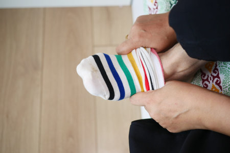 Person putting on striped sock indoors during morning routine