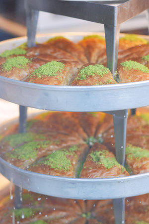 Baklava displayed in a silver tray with nuts and honey drizzle