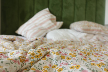 messy bed with floral bedding at early morningの写真素材