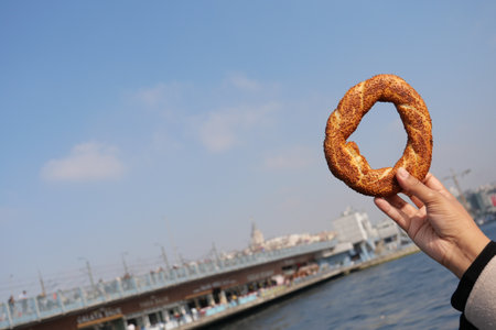Enjoying a simit by the waterfront in a bustling cityの写真素材