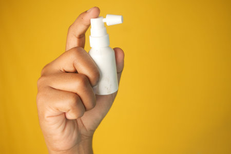 A hand holds a small ear spray bottle with a pump nozzle in focusの写真素材