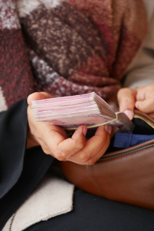 Person holding a stack of papers while seated in a public spaceの写真素材