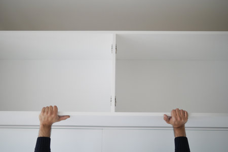 Hands installing a shelf in a white room during daylight hoursの写真素材