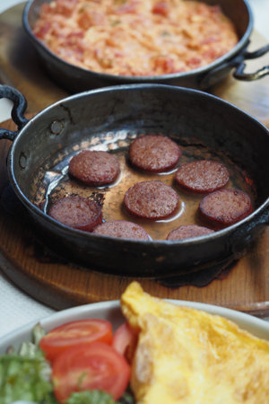 Savory dish of fried sausage and omelette on a wooden tableの写真素材
