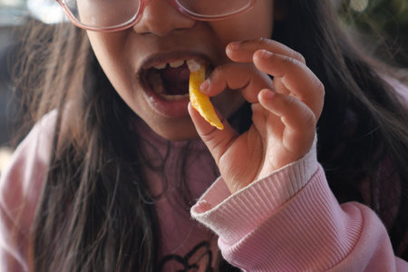 Young girl enjoys a colorful snack outdoors in natural light