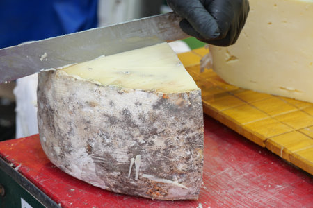 Cutting artisanal cheese at a local market in early afternoonの写真素材