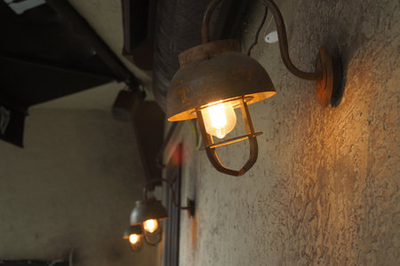 Vintage industrial lighting fixtures illuminate a rustic wallの写真素材