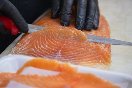Expert chef skillfully prepares fresh salmon in a kitchenの写真素材