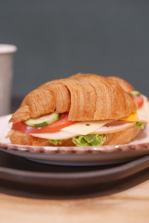 Croissant sandwich with vegetables and cheese on a plateの写真素材