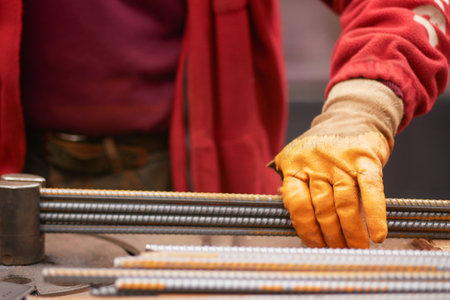 Worker handling steel rebar in industrial workshop environmentの写真素材