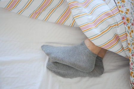 Cozy feet in gray socks under a colorful blanket in morning light