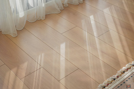 Sunlight reflecting on wooden floor beside sheer curtains at homeの写真素材