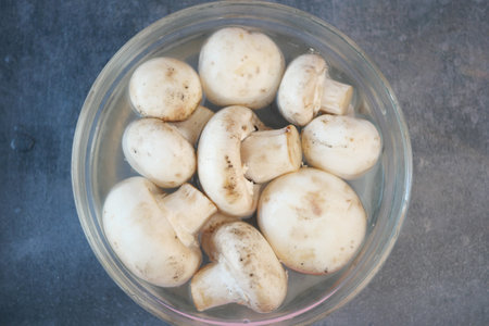 Fresh white mushrooms soaking in water for meal preparationの写真素材