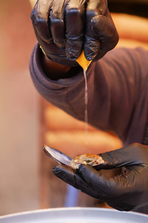 Lemon being squeezed over freshly shucked oyster at seafood market