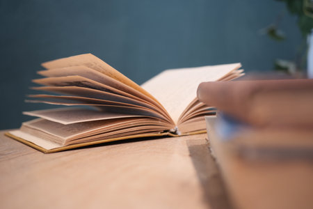 Open book resting on a wooden table with blurred books nearbyの写真素材