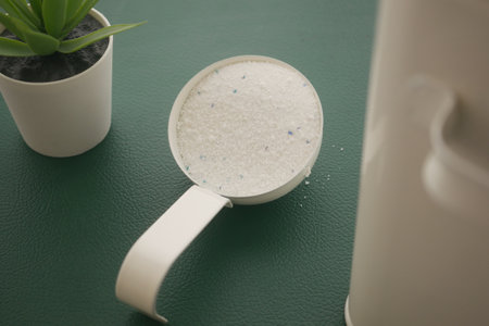 laundry powder in a measuring cup on a green surfaceの写真素材