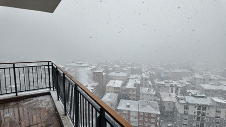Heavy snowfall blankets city skyline on a winter morningの写真素材