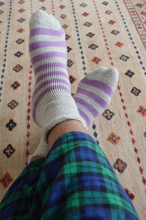 Cozy feet in colorful socks on a patterned carpet at homeの写真素材