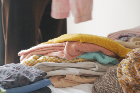Folding colorful clothes on a bed during a weekend choreの写真素材