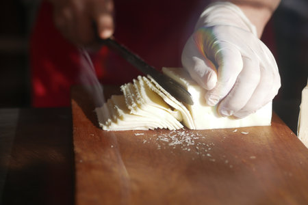 Slicing fresh cheese at a local market during afternoon hoursの写真素材